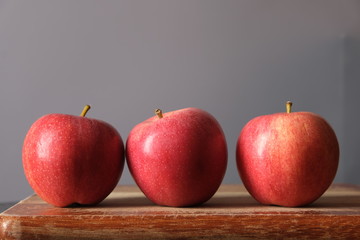 three red apples on a board