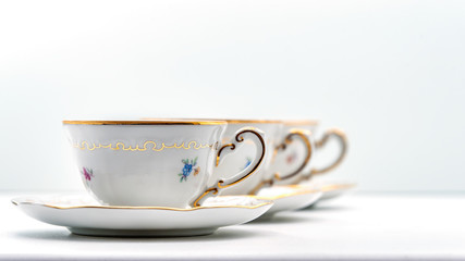 Cups and saucers standing one after another on a white background