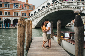 Loving couple on vacation in summer in Venice, Italy - Millennials are kissing in front of the...