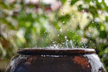 Harvesting downpour rainwater from the roof in the traditional earthen jar, Thailand, Asia.