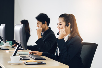 Positive smile young business staff asian woman using headphone and computer.