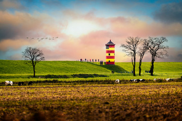 Fototapeta na wymiar Deichlandschaft in Ostfriesland mit Leuchtturm Pilsum.