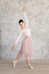 attractive ballerina in pink dress posing in studio.