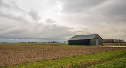 Modern agricultural barn at a plowed field © Ruud Morijn