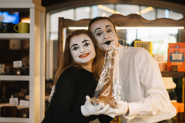 Happy man mime giving a chocolate eiffel tower to his girlfriend. Two happy mimes on a date in the cafe