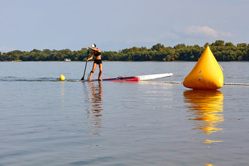 Young girl-surfer with perfect body on stand-up paddle board SUP boarding on Danube river at summer