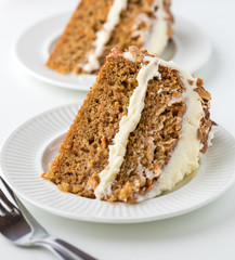 A close up view of two pieces of carrot cake with cream cheese frosting ready for eating.