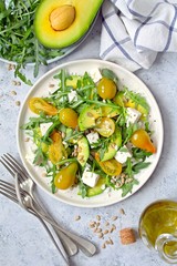 Avocado salad with yellow tomato, feta cheese, arugula and sunflower seeds. Top view with copy space. Healthy food.