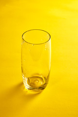 Transparent empty glass in yellow background