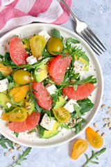 Avocado salad with grapefruits, tomato, feta cheese, arugula and sunflower seeds. Top view with copy space. Healthy eating.