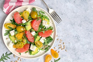 Avocado salad with grapefruits, tomato, feta cheese, arugula and sunflower seeds. Top view with copy space.