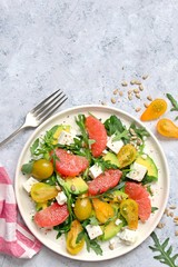 Avocado salad with grapefruits, tomato, feta cheese, arugula and sunflower seeds. Top view with copy space. Healthy eating.
