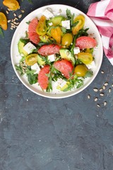 Avocado salad with grapefruits, tomato, feta cheese, arugula and sunflower seeds. Top view with copy space.