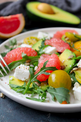 Avocado salad with grapefruits, tomato, feta cheese, arugula and sunflower seeds. Top view with copy space.