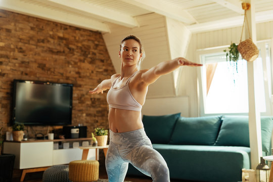 Athletic Woman In Warrior Pose Practicing Yoga At Home.