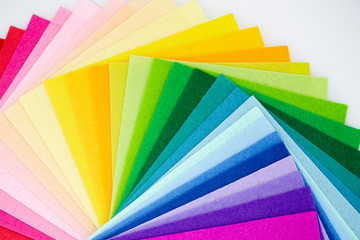 The square pieces of felt spread out by a color spectrum on similarity of a rainbow: from shades of red, pink, yellow, green, blue and bright violette at the end