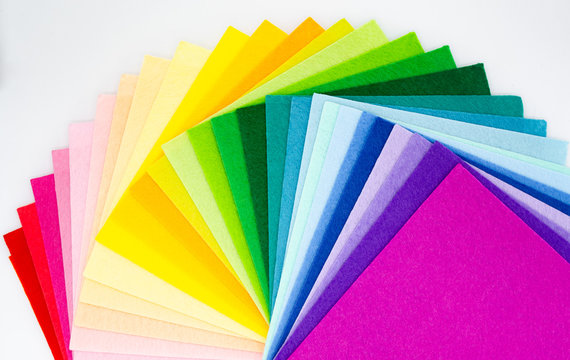 The square pieces of felt spread out by a color spectrum on similarity of a rainbow: from shades of red, pink, yellow, green, blue and bright violette at the end