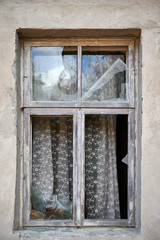 Broken window in old wall of abandoned house