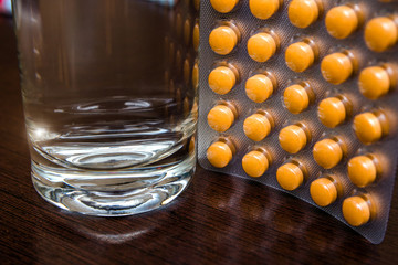 A package of orange tablets is placed on a brown background