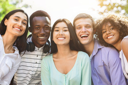 Portrait of cheerful interracial teen friends posing at camera outdoors