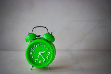 Bright green alarm clock on a light background.