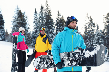 Young snowboarder with friends in snowy mountains. Winter vacation
