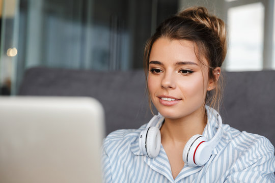 Image of beautiful nice woman with headphones using laptop
