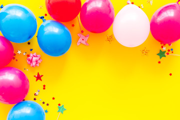 Party concept. Colorful balloons and confetti on yellow background top-down frame copy space