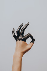 Elegant female hand dipped in black paint on a light background. Isolated. Gesture.