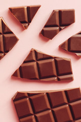 Broken chocolate bar on a pink background