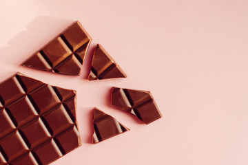 Broken chocolate bar on a pink background
