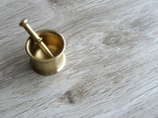 Mini brass Mortar and Pestle on wooden background with space for text.