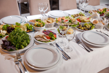 Salads and gums . Set of a dish with spoon, fork and knife on white table.Table setting on white table .