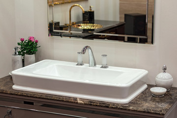 A beautiful washbasin with a silver chrome tap and fittings. Marble sink, led mirror, white dispenser, modern bathroom design.