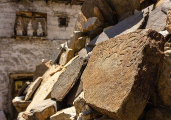 Fototapeta premium An old mani stone with Tibetan prayers scrawled on it outside an ancient Buddhist monastery in the village of Nako in Kinnaur, India.