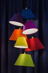 Hanging color lampshades on dark background. Composition of multi-colored chandeliers