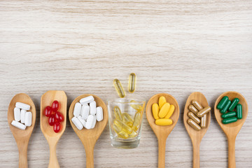 Medicine, vitamins and antioxidant supplements in wood spoon on table