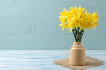 Spring flowers, yellow daffodils in a vase on a blue wooden background. place for text © MK studio