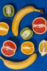 Juicy ripe fruits on a wooden blue background. Flat lay, top view. Pop art design, creative summer concept. Fruits in a minimalist style.Vertical orientation