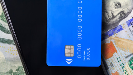 Contactless payment system. NFC payment system. A smartphone and a credit card are on dollar bills