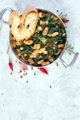 Stewed beans with black cabbage served with toasted bread. Vegetarian and vegan food. Top view with copy space.