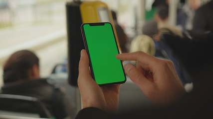 NEW YORK - May 19, 2019: Slow motion man young hand uses holding a mobile telephone with a vertical green screen background tram inside window key smartphone technology touch message display close up