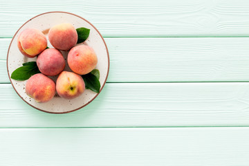 Summer fruits. Ripe red peaches on plate on green wooden table top-down copy space