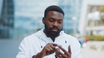 Smiling african american man uses futuristic glass phone walk at city look at camera smile nanosmartphone transparent electronic future global information innovation interface touch web slow motion