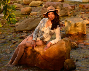 Beautiful latina girl lounging on river rock