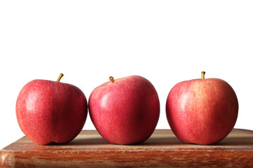 three red apples on a board