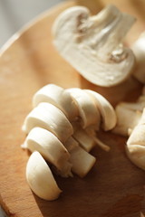 sliced champignon mushrooms on a wooden sunny board, close-up