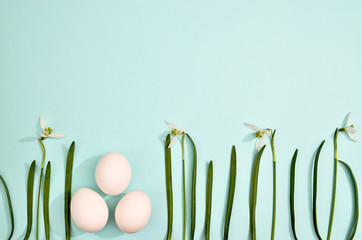 White eggs with green myrtle leaves pattern on mint color background. Spring and Easter holiday concept with copy space.