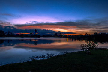 Obraz premium Wallpaper blurred nature of the twilight light in the evening by the large water basin surrounded by big trees, the integrity of the forest