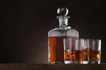 Bottle of whiskey with glasses on brown background